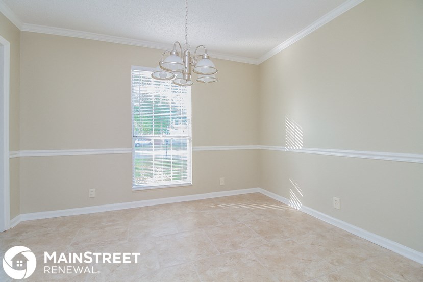 an empty dining room with beige walls and a window