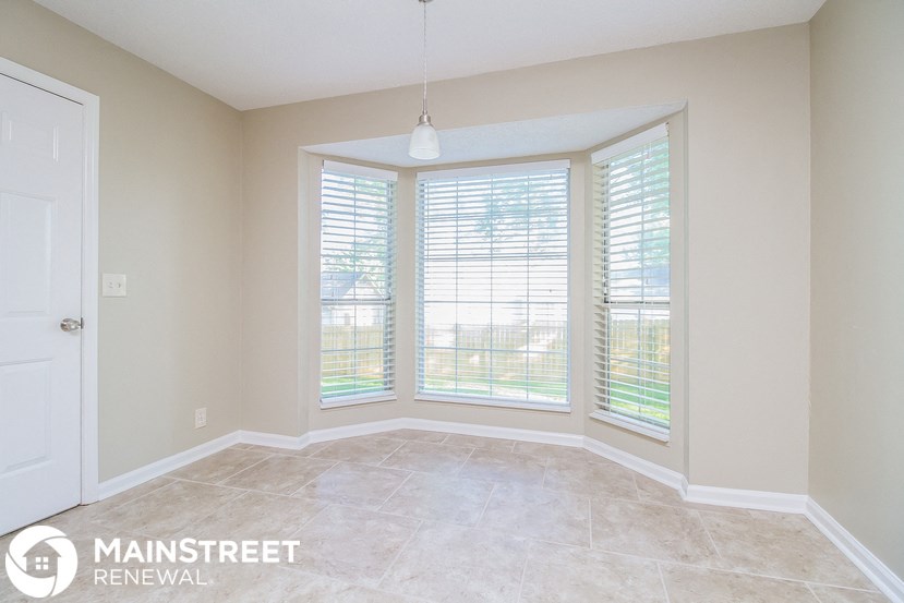 a living room with three windows and a tile floor