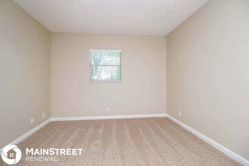 an empty room with beige carpet and a window