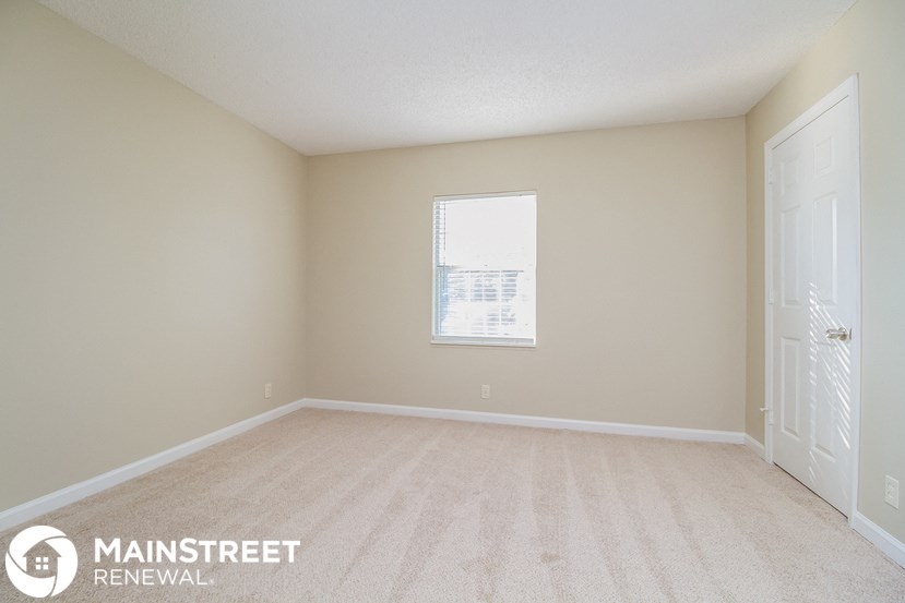 a spacious living room with a white door and a window