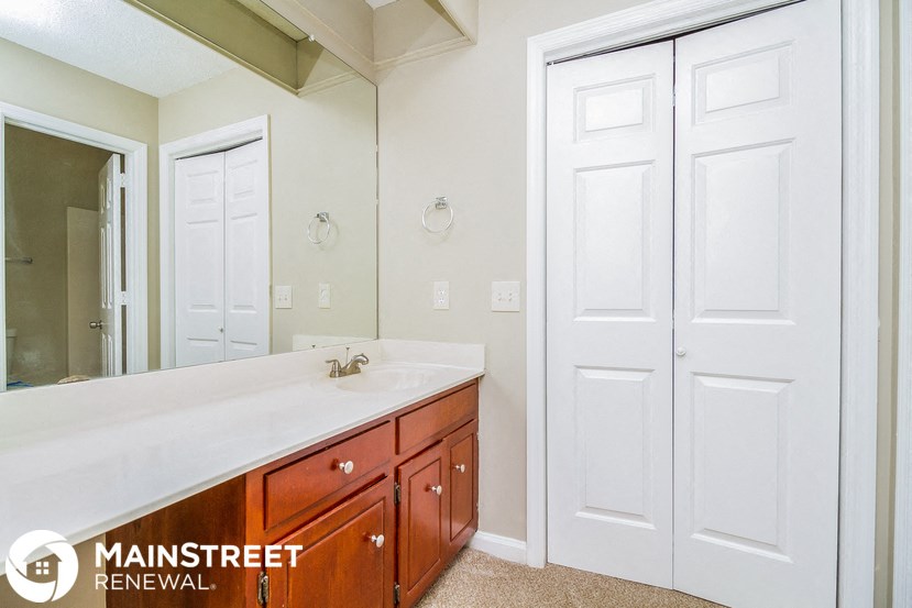 a bathroom with a sink and a mirror and two closets
