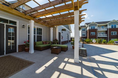 a patio with a pergola in front of an apartment building