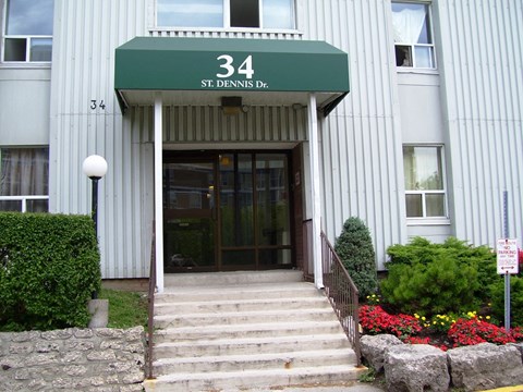 The front of a building with a green awning that says 34 St. Dennis Dr.