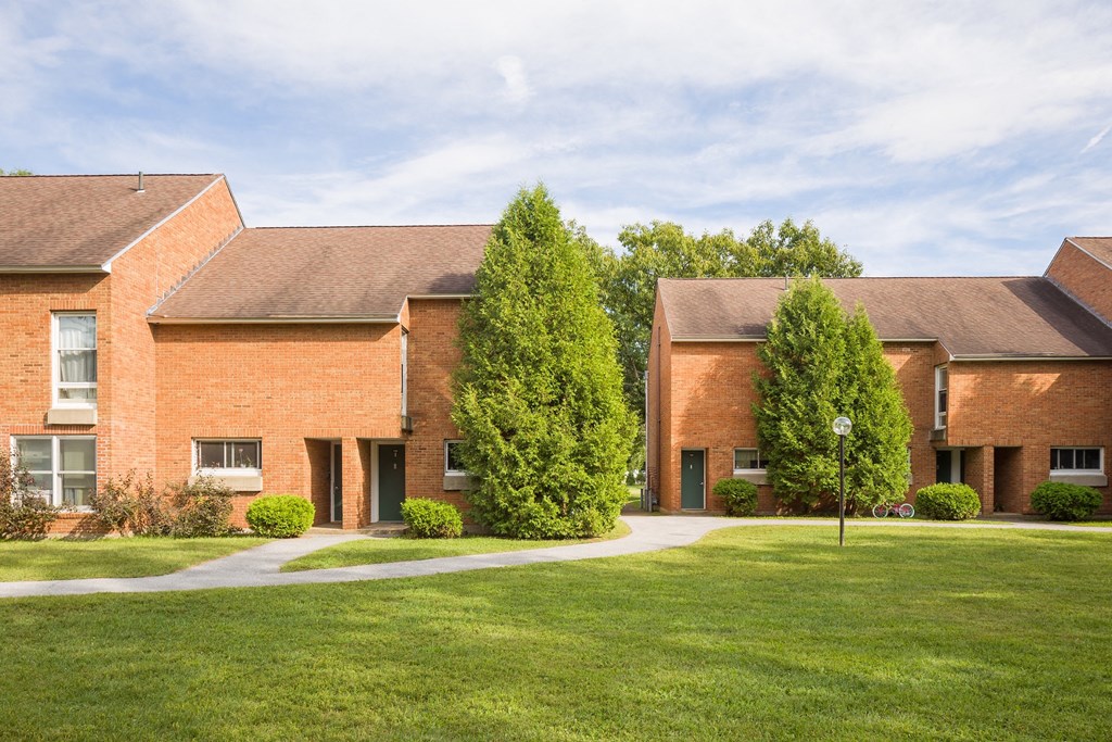 a yard in front of a brick house with a green lawn