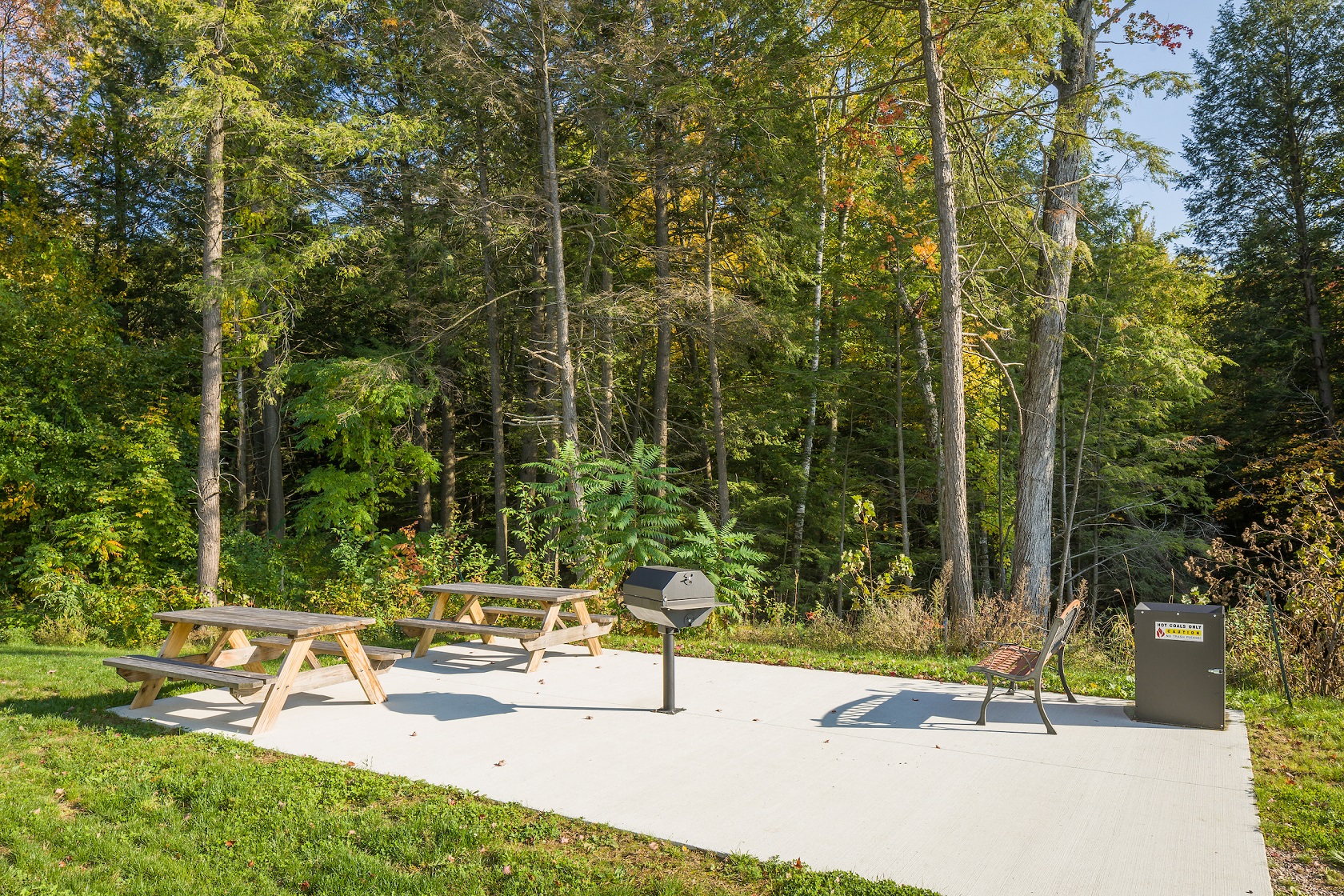 a picnic area with two picnic tables and a smoker
