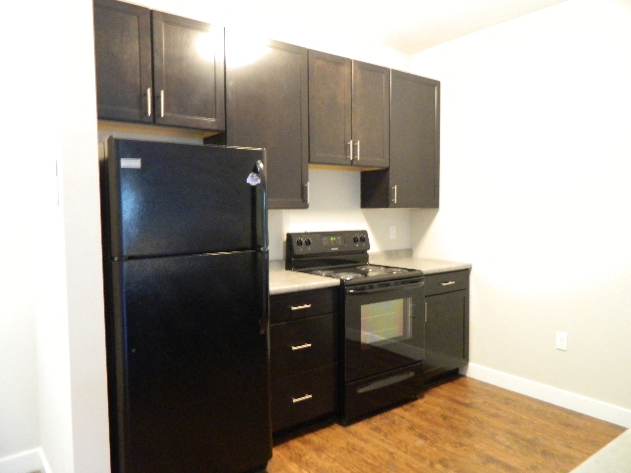 an empty kitchen with black appliances and a refrigerator