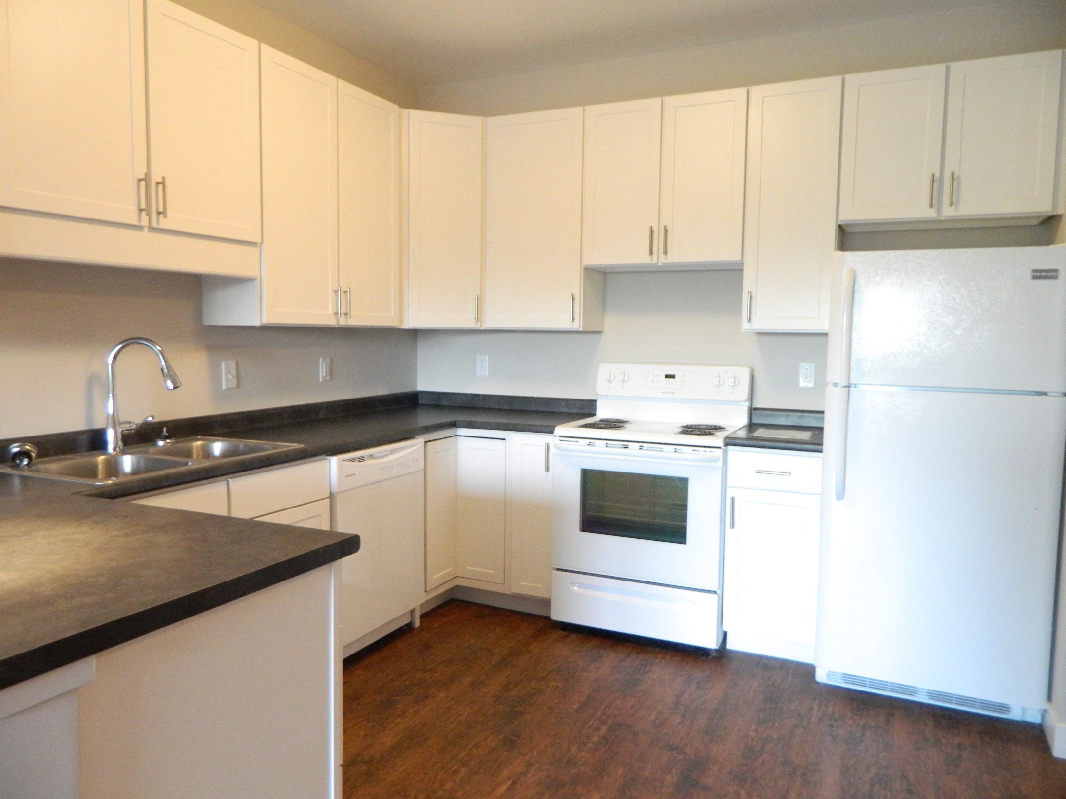 an empty kitchen with white appliances and white cabinets