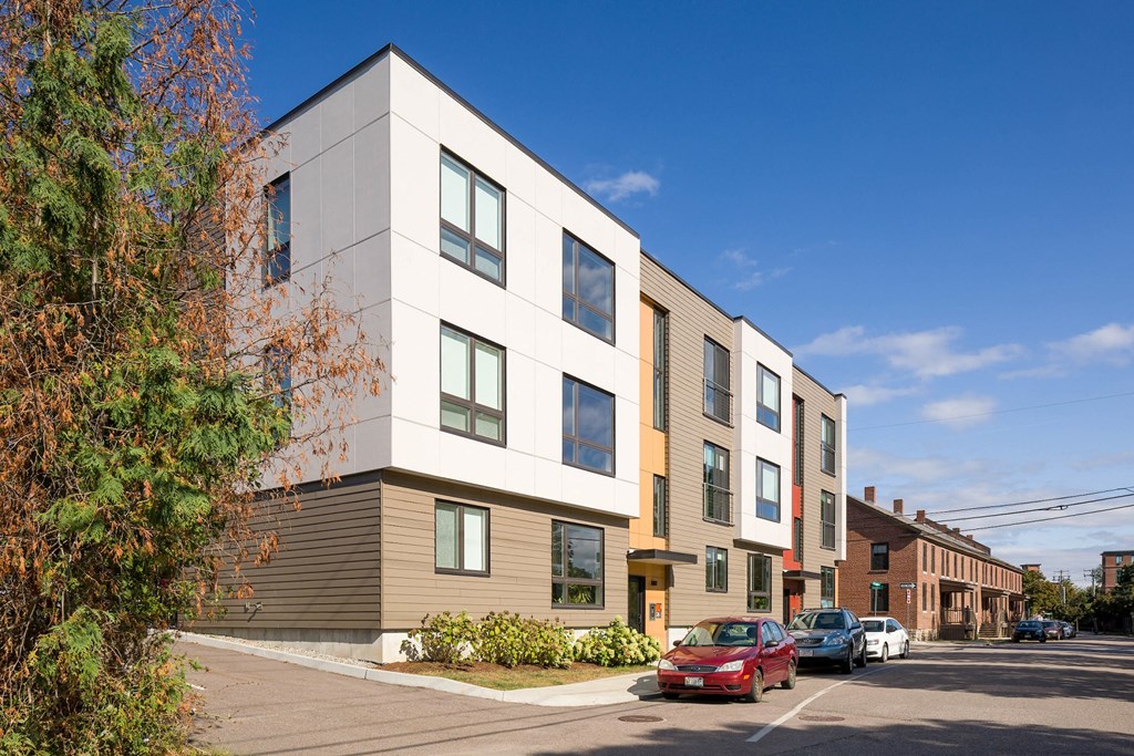 a new apartment building on a city street with cars parked