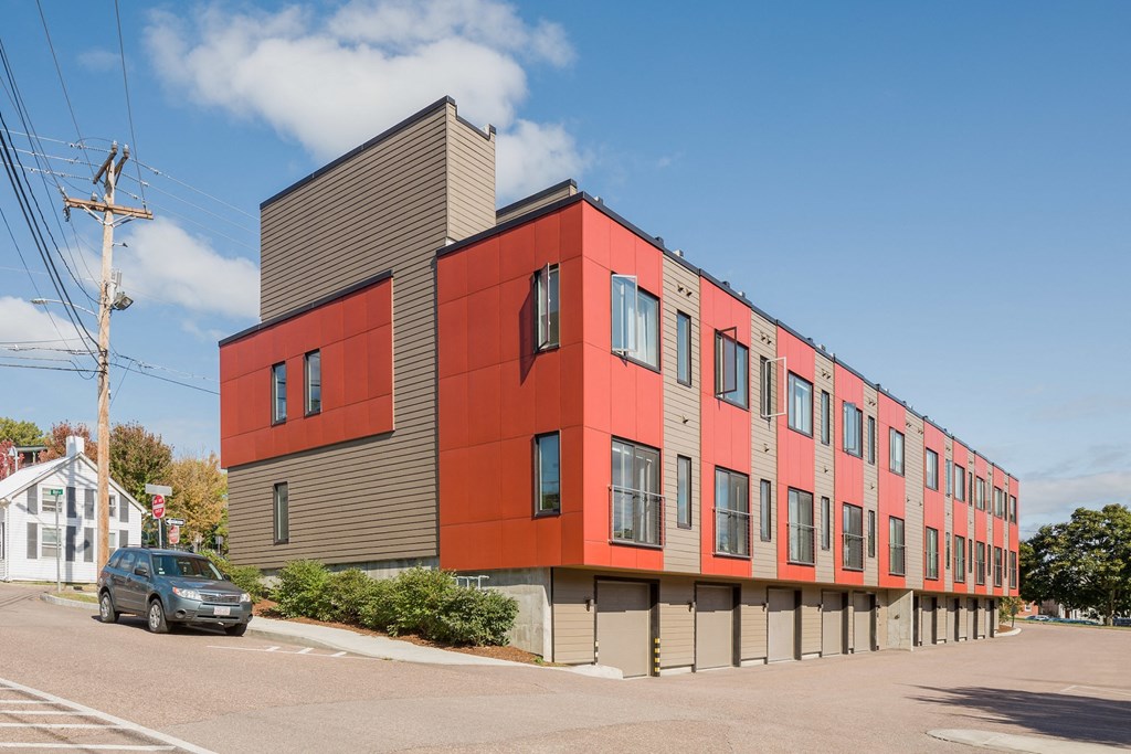 a red apartment building with a car parked in front of it