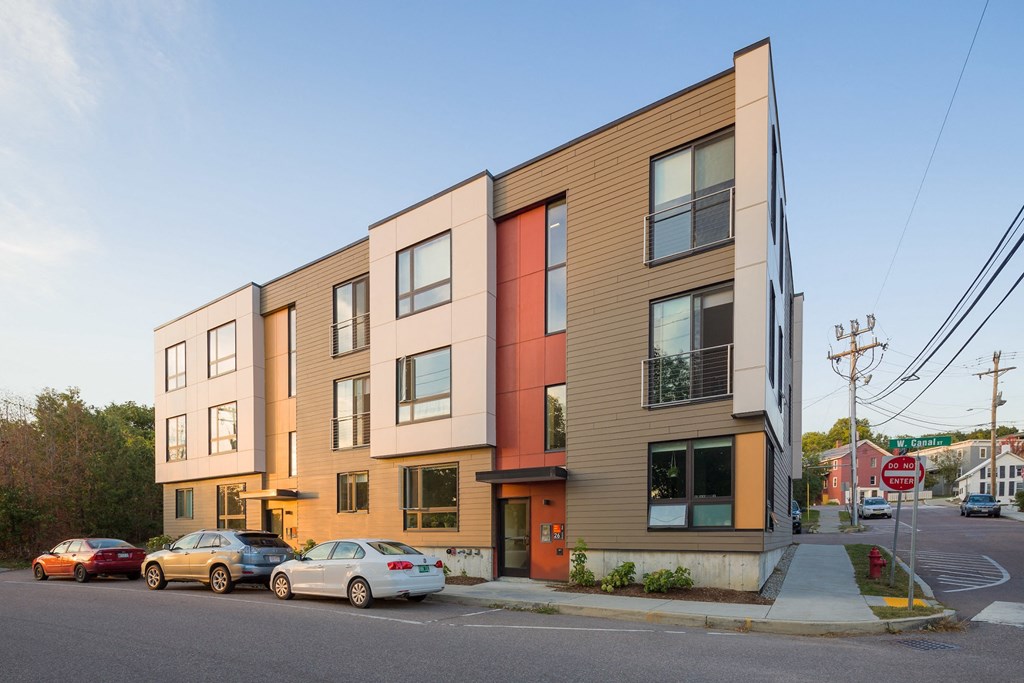 a row of apartment buildings on a city street with cars
