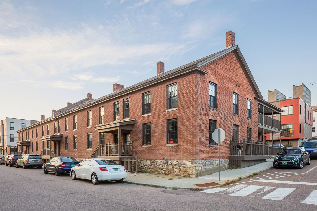 a red brick apartment building on a city street with parked cars