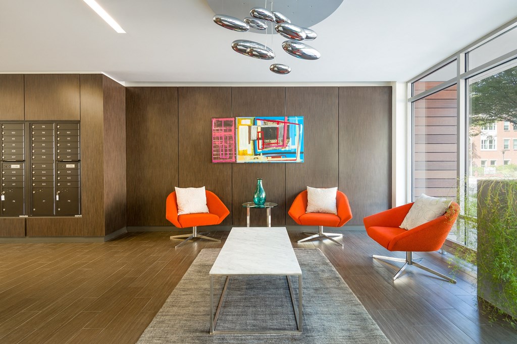 a living room with orange chairs and a white rug and a large window