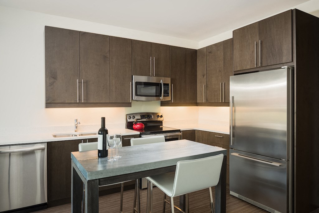 a kitchen with stainless steel appliances and a table with white chairs