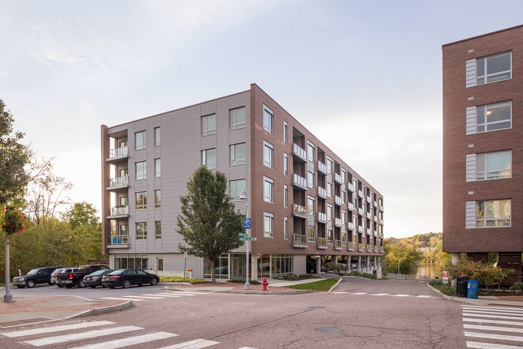 an apartment building on the corner of a street with parked cars