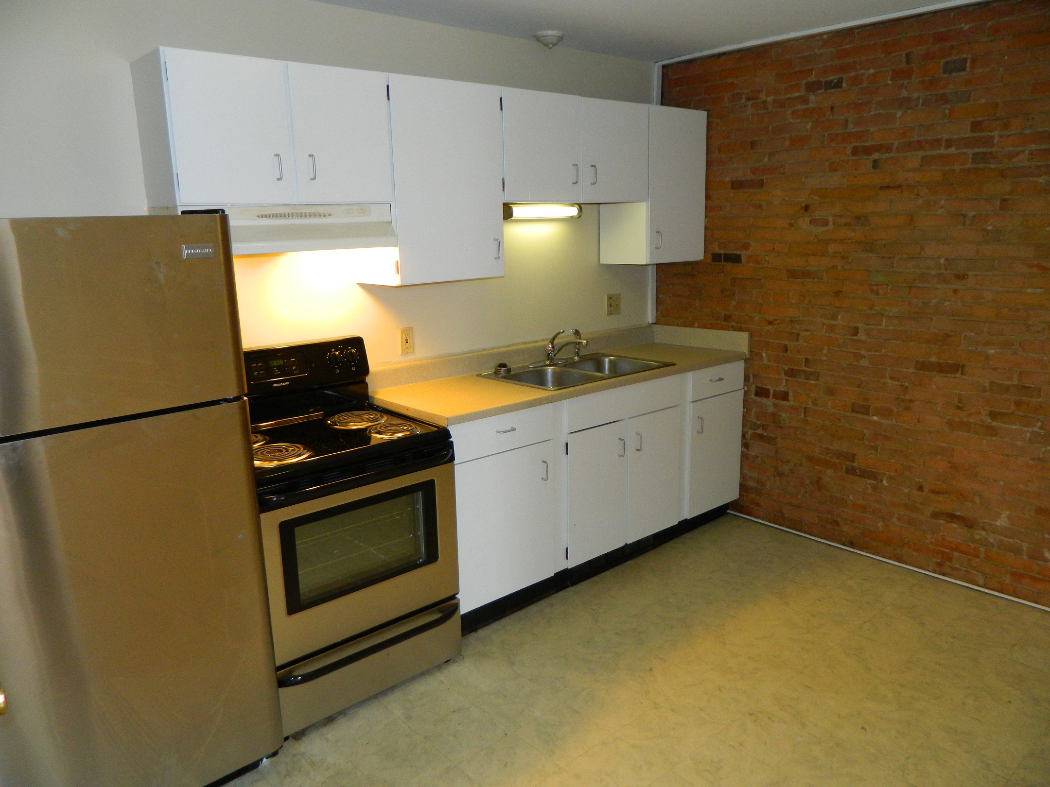 an empty kitchen with a stove refrigerator and sink
