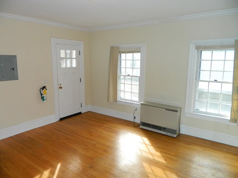 an empty living room with wooden floors and a white door and window