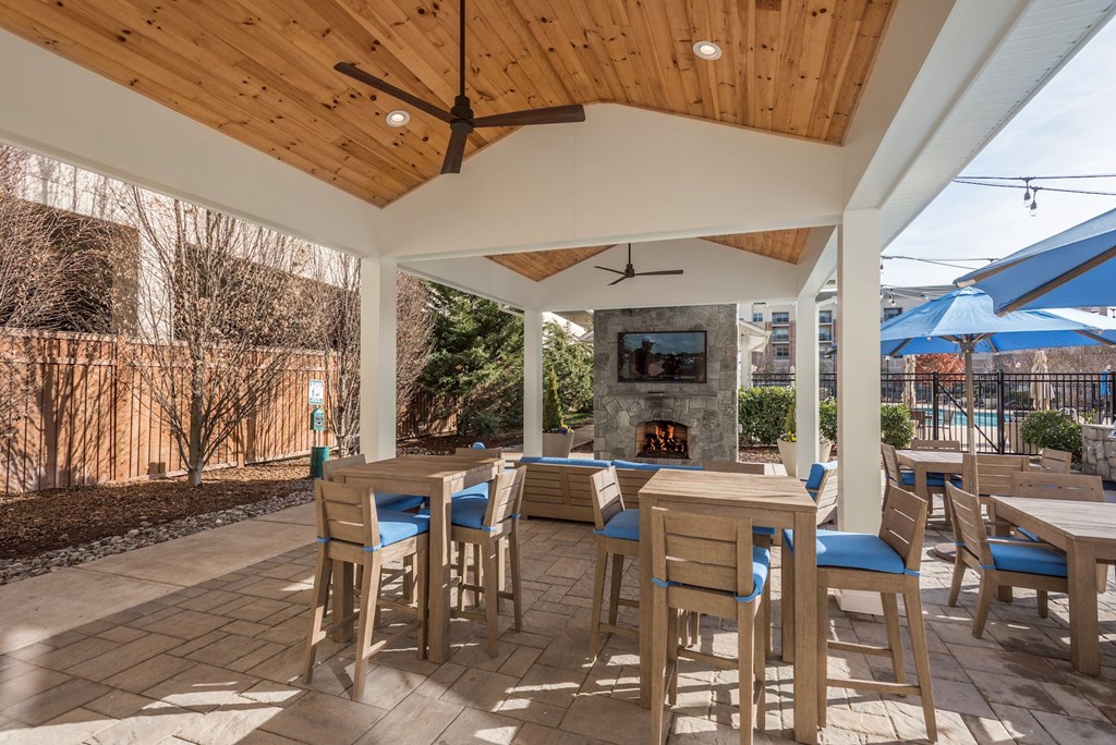 a patio with tables and chairs and a fireplace