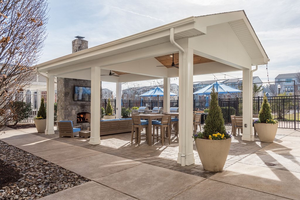 a covered patio with tables and chairs and a fireplace