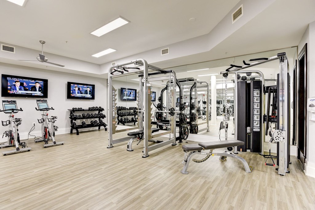 a gym with weights machines and televisions on the wall