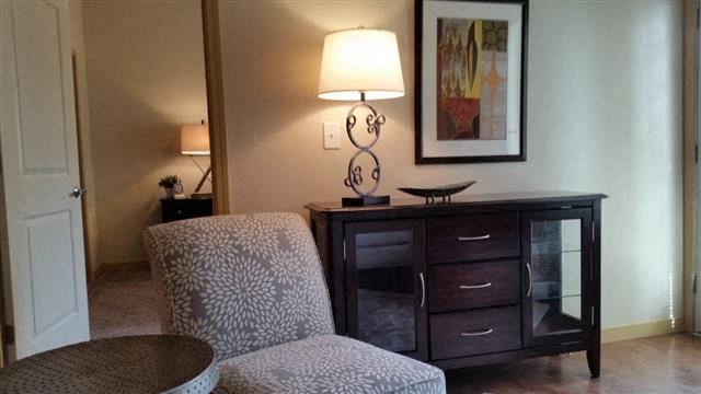 a living room with a chair and a desk with a lamp