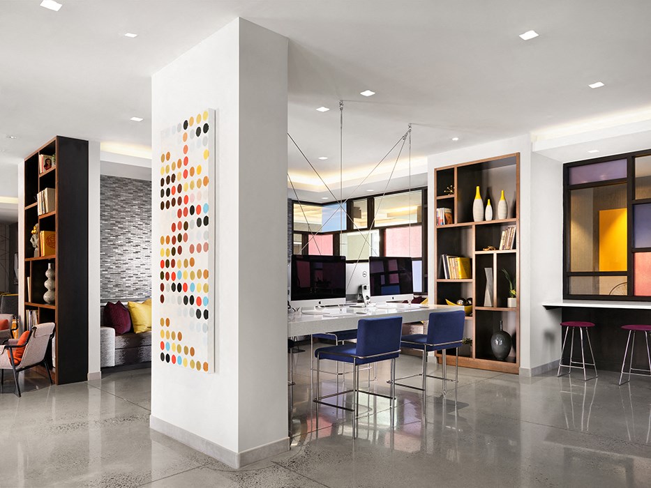 a lobby with a bar and chairs and a wall with colorful shelves