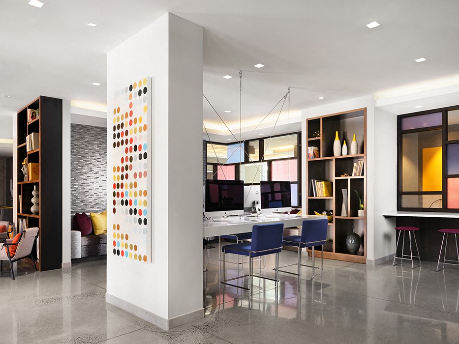 a lobby with a bar and chairs and a wall with colorful shelves