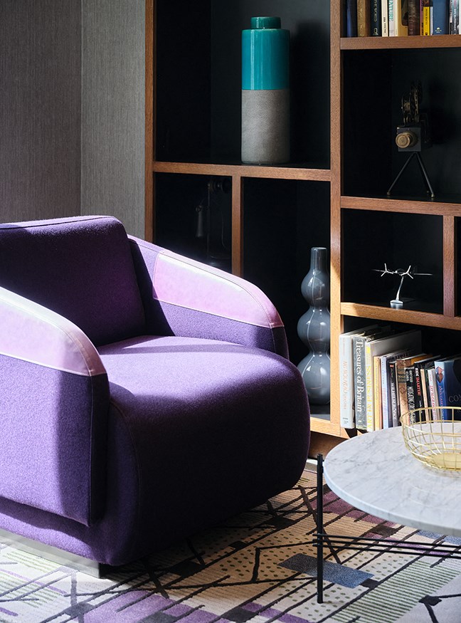 a living room with a purple chair and a book shelf