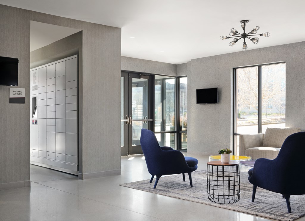 a living room with blue chairs and a rug and a door