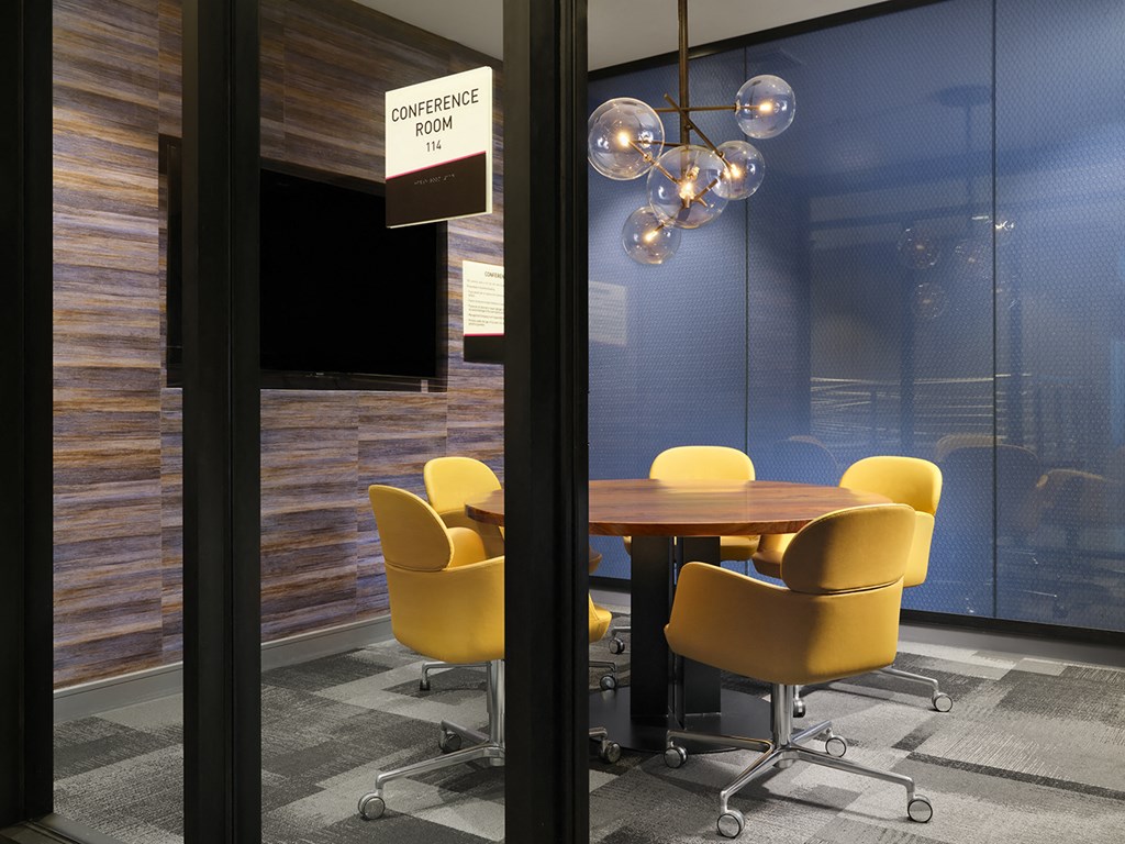 a conference room with yellow chairs and a wooden table