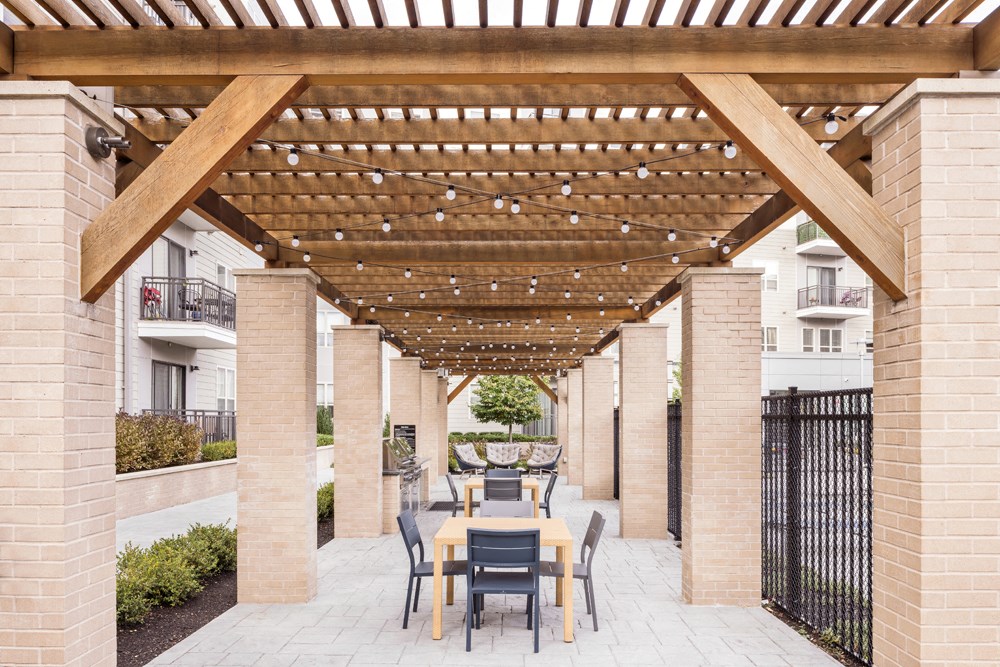 a patio with a table and chairs under a wooden pergola