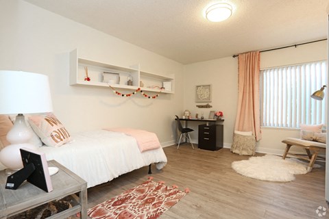 A bedroom with a white bed and a desk with a chair.