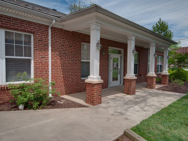 the front of a brick house with a porch and a white door