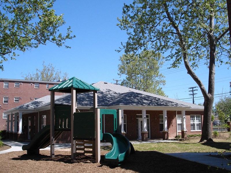 a playground with a swing set in front of a house