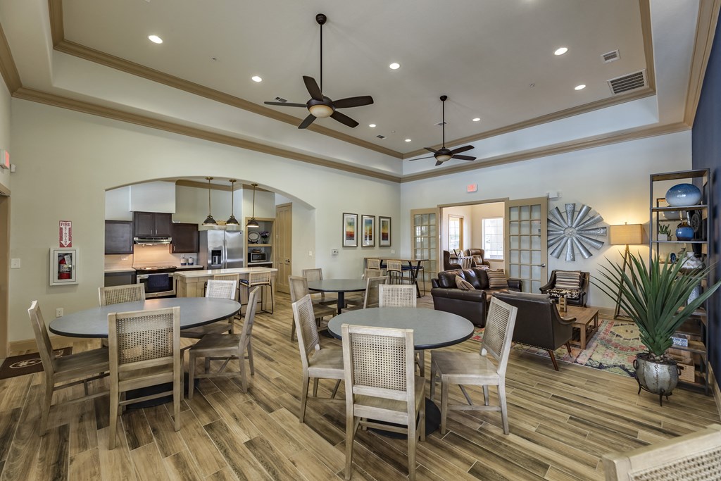 a large living room with tables and chairs and a kitchen