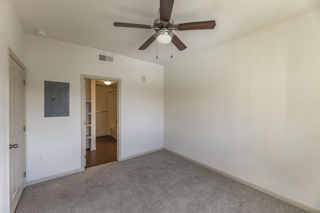 an empty living room with a ceiling fan and white walls