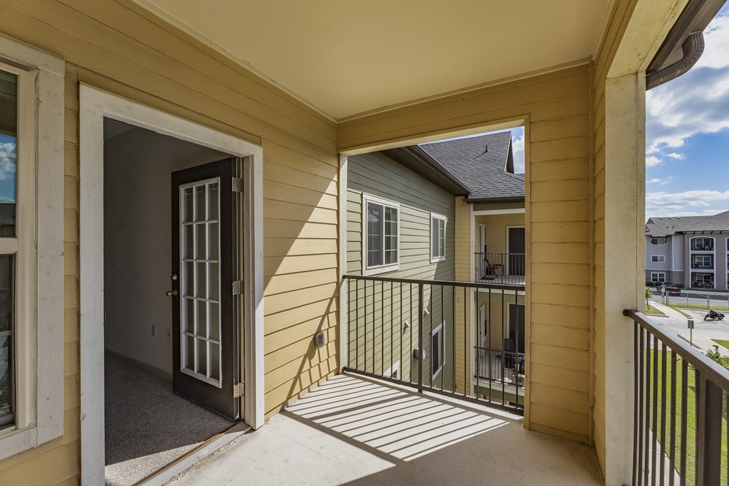 the view from the balcony of a yellow house with a door open to a balcony