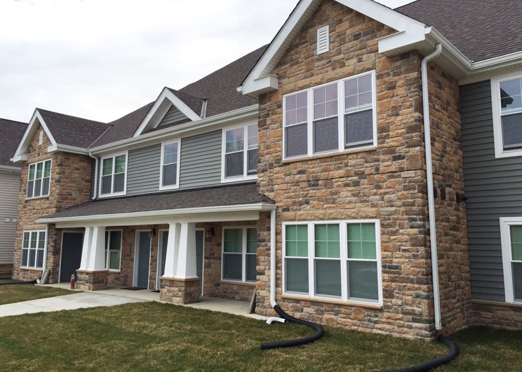 the front of a brick house with windows and a sidewalk