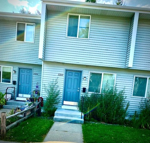 a white house with blue doors and a sidewalk