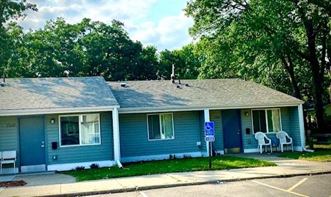 a blue house with two white chairs in front of it