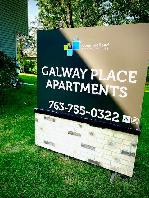 a sign for galaxy place apartments on the grass
