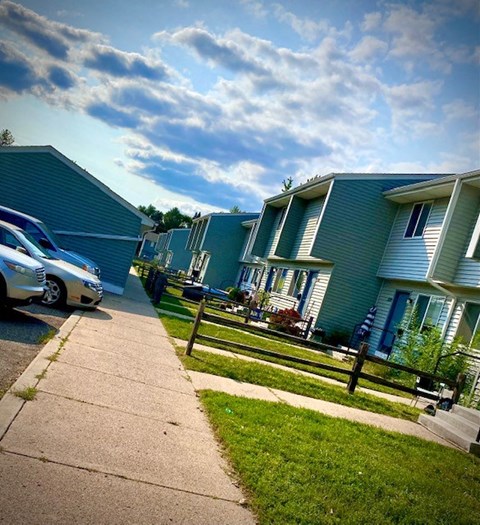 a row of houses with cars parked on the street