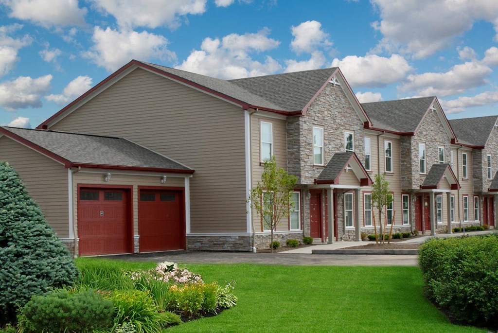 a row of houses with red doors and a green lawn