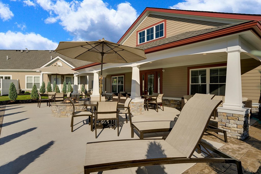 a patio with tables and chairs and umbrellas in front of a house