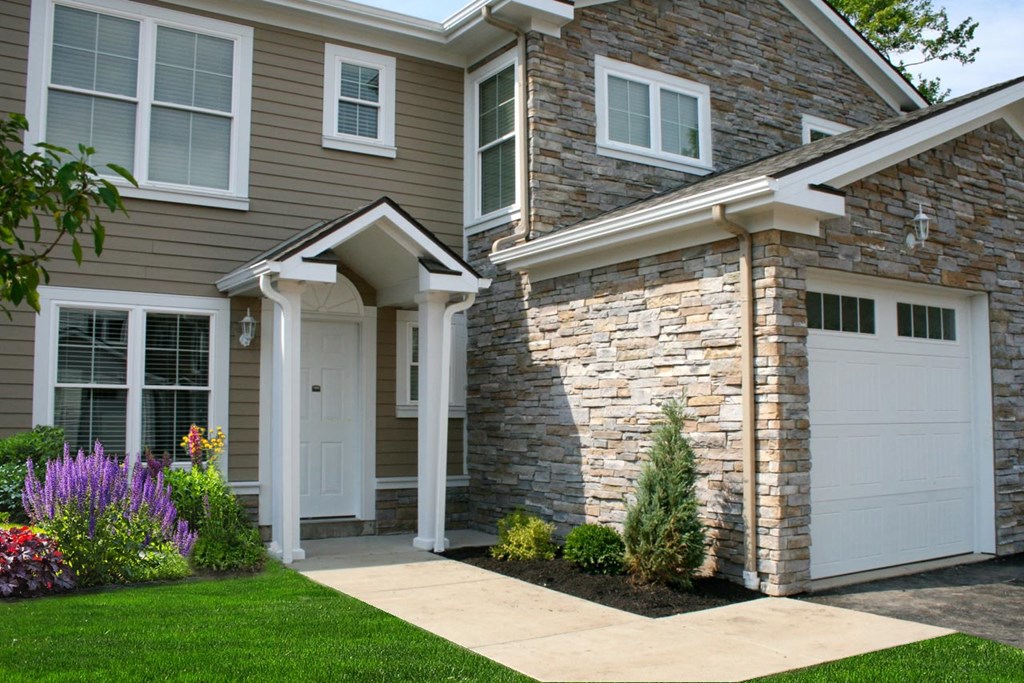 a home with a white garage door and a stone facade