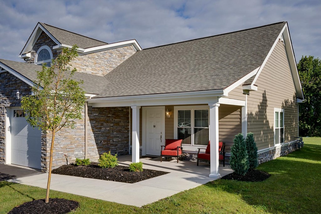the front of a house with a porch and a tree
