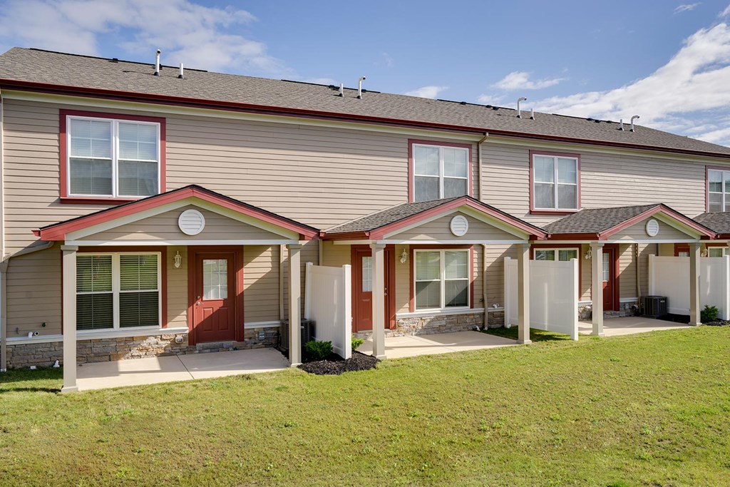 a row of houses with red doors and a green yard