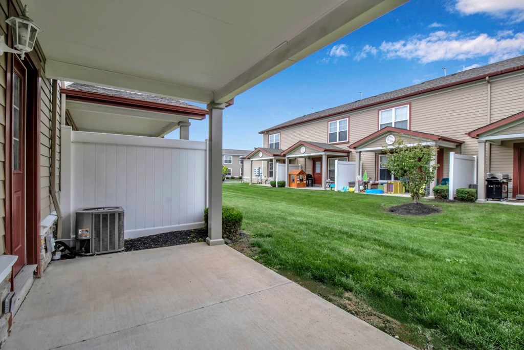 a driveway leading to a group of houses with a grass yard