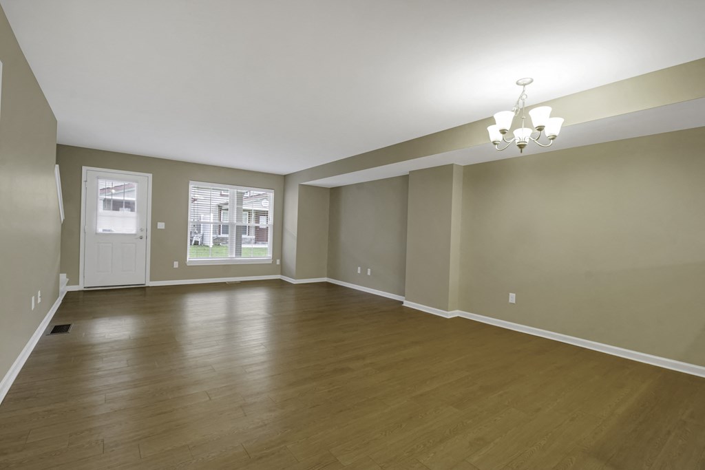 an empty living room with wood floors and a window
