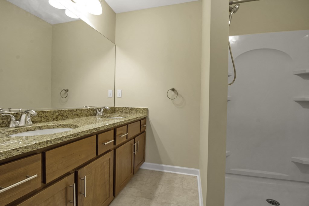 an empty bathroom with two sinks and a shower
