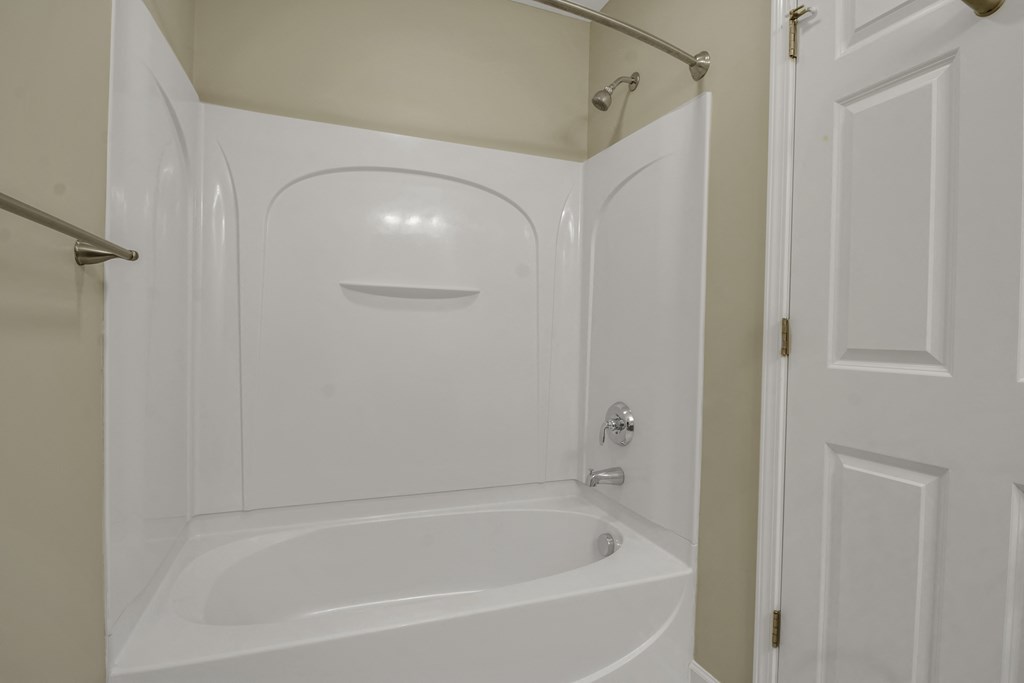 a small bathroom with a white tub and shower and a white door